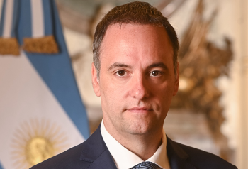 Manuel Adorni en retrato oficial con bandera argentina de fondo